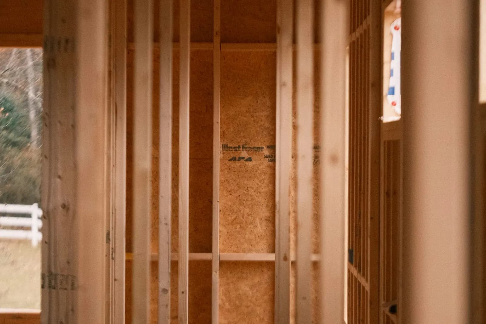 Wood-framed room during construction with open walls and tools on site